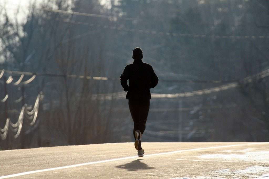 دونده‌ای در حال دویدن روی آسفالت در یک روز سرد
