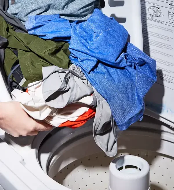 فردی در حال قراردادن لباس‌های ورزشی در لباس‌شویی