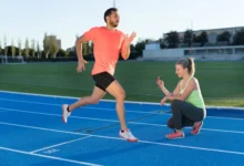 دونده آقا در حال دویدن روی پیست در کنار خانم مربی با کرنومتر در دست برای ثبت زمان دویدن دونده مرد