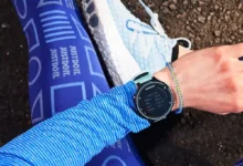 دونده نشسته روی زمین در حال تماشای ساعت هوشمند خود