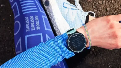 دونده نشسته روی زمین در حال تماشای ساعت هوشمند خود