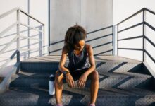 دونده خانم نشسته روی پله و خسته از نظر روانی در کنار بطری آب