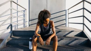 دونده خانم نشسته روی پله و خسته از نظر روانی در کنار بطری آب