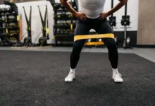 یک ورزشکار در حال انجام اسکوات کش مقاومتی در باشگاه